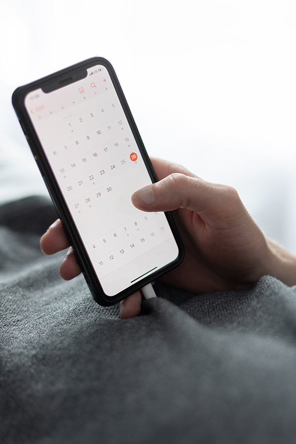Hand hält Smartphone mit geöffnetem Kalender